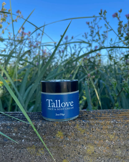Tallove Tallow Face &amp; Body Cream 2 oz jar set against Vancouver Island wildflowers and grass, natural grass-fed tallow skincare handmade in British Columbia